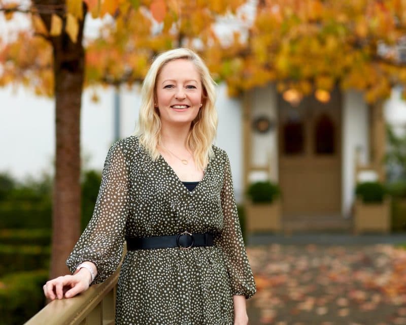 a smiling lady standing outside of grove