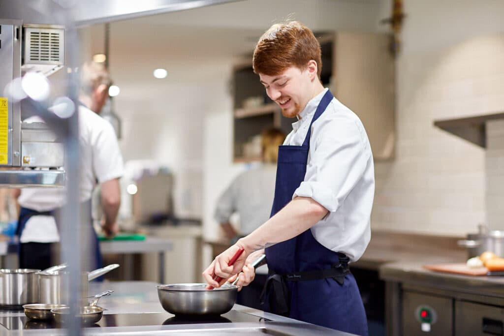 smiling grove chef stirring food in the bowl in the kitchen