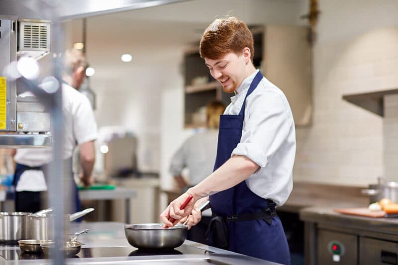 smiling grove chef stirring food in the bowl in the kitchen