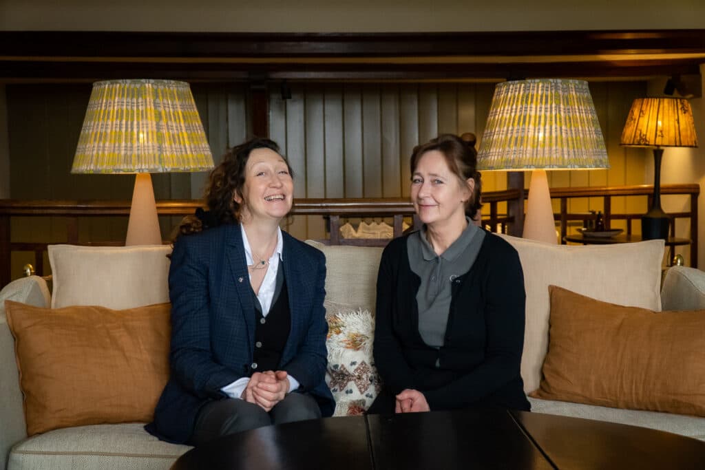 two ladies smiling sitting on the couch